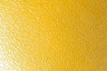 Bright yellow textured grainy surface, lemon like pattern close-up.