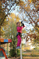little girl overcomes rope obstacles in the trees