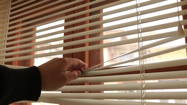 Close-up Of Man Looking Through Window Blinds