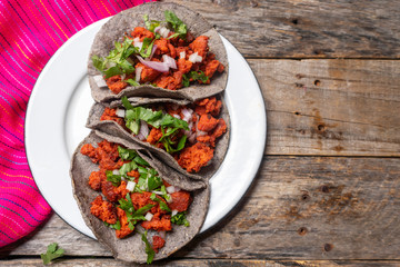 Mexican chorizo tacos with blue corn tortillas on wooden background