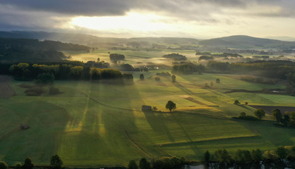 beautiful autumnal landscape with ground fog in the early morning with sunbeams 