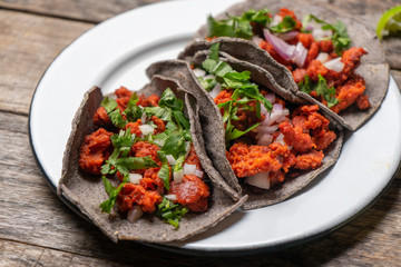 Mexican chorizo tacos with blue corn tortillas on wooden background