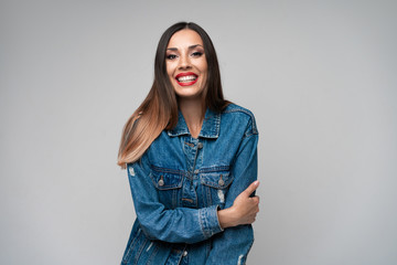 Beautiful caucasian girl in a denim jacket posing in the studio on a white background.