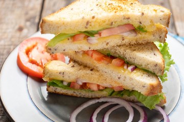 Grilled cheese sandwich with tomato and whole grain bread on wooden background