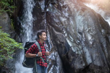 Fototapeta na wymiar Young hiker standing in front of the waterfall with backpack. travel concept.