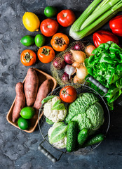 Fresh organic vegetables, fruits on a dark background, top view. Healthy diet food concept. Sweet potato, savoy cabbage, sweet peppers, celery, cucumbers, tomatoes, persimmon - vegetarian food