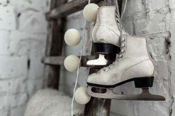 A pair of white leather sports skates hang on a cord on the wall. Good New Year spirit. Beautiful calm background