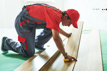 worker laying laminate floor covering at home renovation