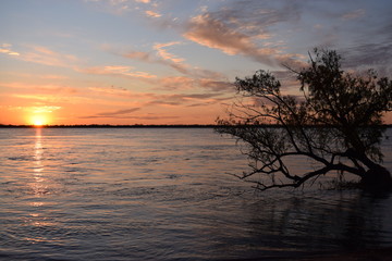 Landscape of a sunset on the river with clouds and trees