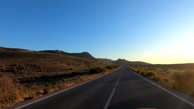 point of view, driving on a rural road at dawn with sunbeam, in Cabo de Gata, Almeria, Andalusia, Spain