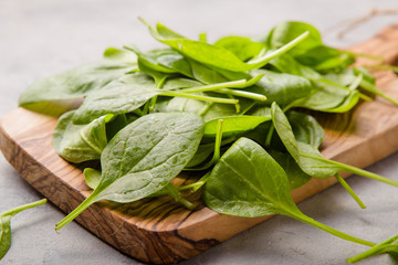Baby spinach leaves on grey concrete background, top view, copy space. Clean eating, detox, diet...