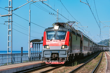 Fototapeta na wymiar Passenger double deck train moves along the platform by the Black sea coast. Sochi. Russia.