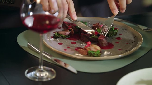 Male hands cutting meat steak at restaurant. Business man dining in restaurant