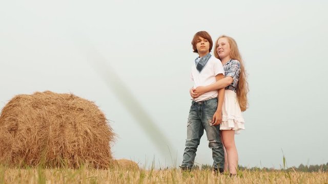 Teenager couple embracing on countryside field on haystack background. Young couple teenager girl and boy hugging on harvesting field in village