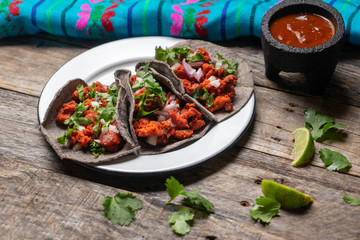 Mexican chorizo tacos with blue corn tortillas on wooden background