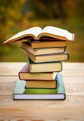 An open book lying on a stack of books in on a wooden table. Vertical 