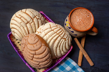 Mexican hot chocolate with sweet conchas bread on dark background