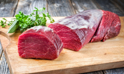 Dry aged beef fillet steak natural offered as closeup on a wooden cutting board - obrazy, fototapety, plakaty