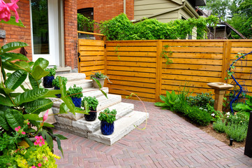 Contemporary with traditional elements, this beautiful small urban backyard garden features a red...