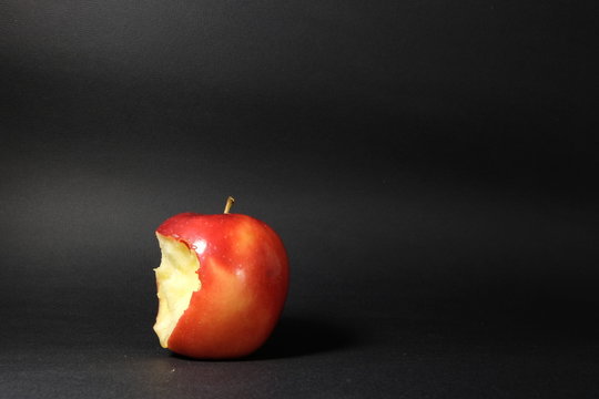 angebissener Apfel vor schwarzem Hintergrund