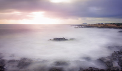Idyllic rocks bathed by an ethereal sea under a spectacular cloudscape. Long day exposure photography combining neutral density filters to achieve the so-called silk effect in the water