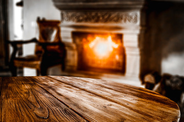 Wooden top with empty space for advertising products with blurred fireplace background in a cozy...