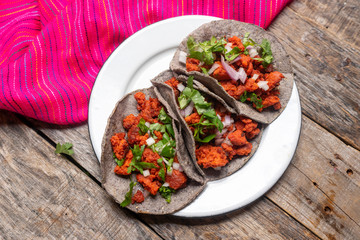 Mexican chorizo tacos with blue corn tortillas on wooden background