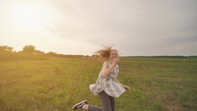A girl with long hair amusingly runs around the field showing off her long hair.