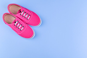 Pink sneakers for a girl on a blue background. Free space for text. Sale of children's clothing. Top view.