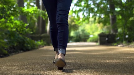Low angle shot of Young woman walking outside in city park during the day. Focused only on the feet and shoes with shallow depth of field - Powered by Adobe