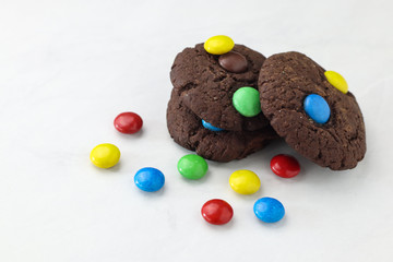 Tasty brownie cookies with colorful candies on table, close up