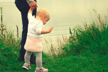 Dad teaches daughter to walk in nature. Father and daughter. First steps.