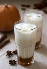 Homemade pumpkin latte in tall glasses and pumpkin on a linen tablecloth. Rustic style.