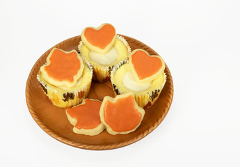 Homemade cheesecake cupcakes in fall colored orange, brown, and white paper holders on an orange plate against a white background.