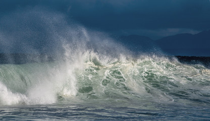 Fototapeta premium Seascape. Powerful ocean wave on the surface of the ocean. Wave breaks on a shallow bank. Stormy weather, stormy clouds sky background.