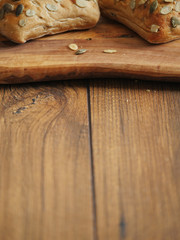 Two sourdough rolls with pumpkin seed on a wooden board and table, Warm brown tones. Bakery product. Close up. Vertical image.