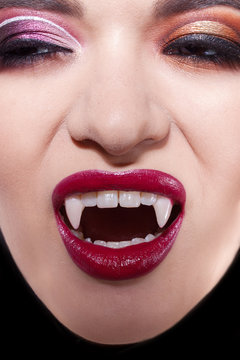 Sexy vampire. Women's lips with red lipstick. Screaming mouth with vampire fangs,