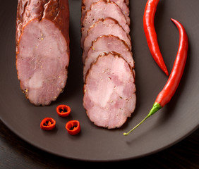 Smoked sausage with spicy pepper on a dark plate