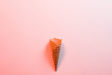 Dessert shop. Flat lay of homemade crispy waffle ice cream cone on pink background. Copy space.