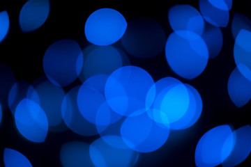 Blue bokeh lights. Glowing circles, lens flare on black abstract background. Copy space.