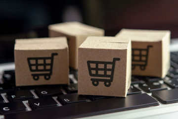 Online shopping - Paper cartons or parcel with a shopping cart logo on a laptop keyboard. Shopping...