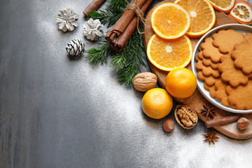 Winter composition. Flat lay of Gingerbread cookie, Cinnamon sticks, cones, sprigs of spruce, slices of orange, mandarin, nuts, powdered sugar on black background. Copy space