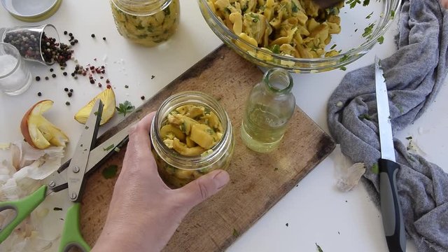 Personal perspective of woman hands preparing Amanita caesarea (known as Caesar's mushroom). Put the mushrooms in jars in oil