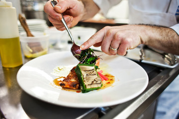 chef preparing and styling food dish in restaurant kitchen