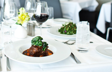 clean white table setting with meal and wine at elegant restaurant 