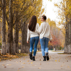 Two girlfriends in a white woolen sweater and blue jeans