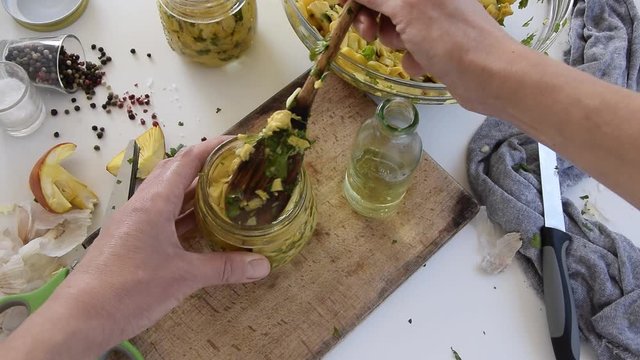Personal perspective of woman hands preparing Amanita caesarea (known as Caesar's mushroom). Put the mushrooms in jars in oil
