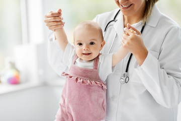 medicine, healthcare and pediatrics concept - female pediatrician or neuropathist doctor or nurse checking smiling baby girl patient's health at clinic or hospital - obrazy, fototapety, plakaty