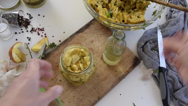 Personal perspective of woman hands preparing Amanita caesarea (known as Caesar's mushroom). Put the mushrooms in jars in oil