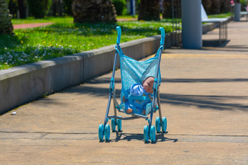 forgotten doll sitting in a toy stroller on the path of the Park